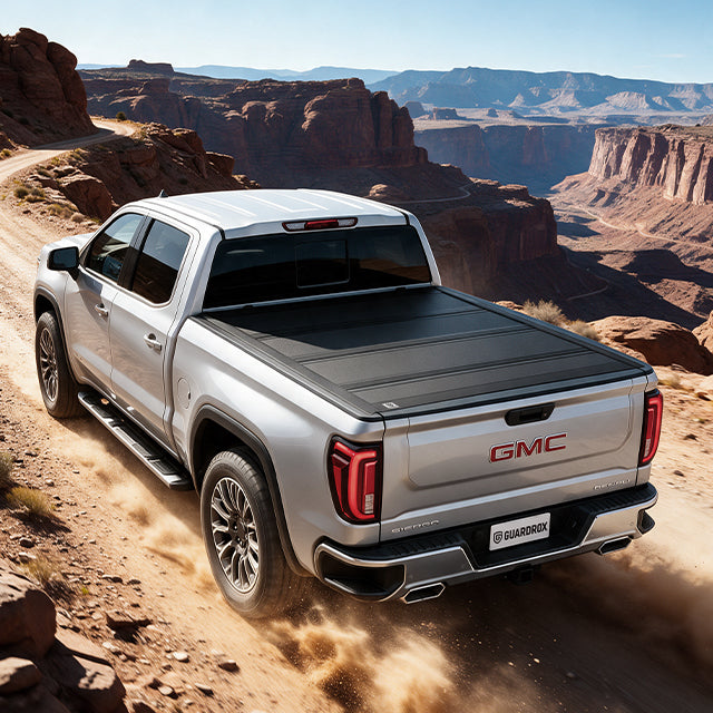 gmc sierra with a hard tonneau cover speeding on a gravel mountain road, dust trailing behind