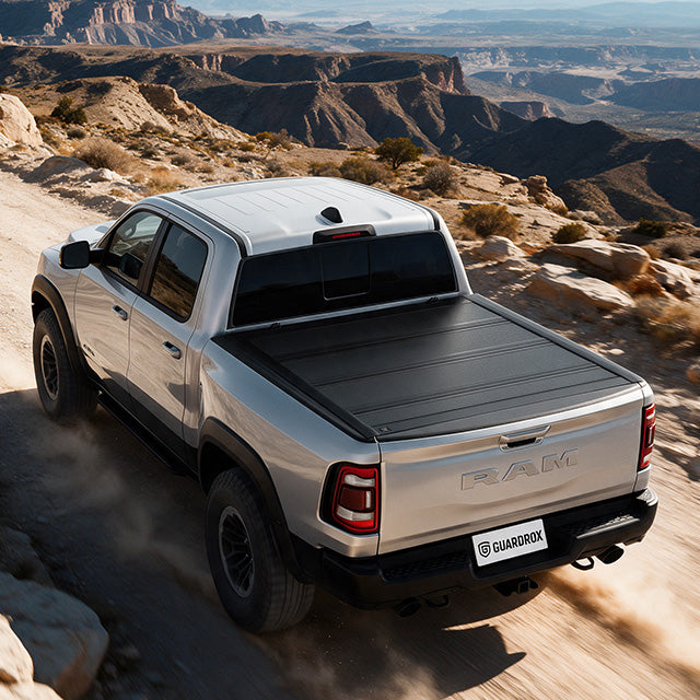 ram 1500 with a hard bed cover speeding on a gravel mountain road, dust trailing behind