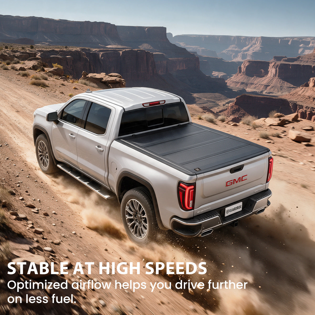 Hard quad-fold tonneau cover riding steady on a GMC Sierra 1500 cruising a mountain highway for better fuel economy