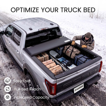 Folding truck bed cover propped open with firewood, skis, and duffels loaded in a snowy pickup bed