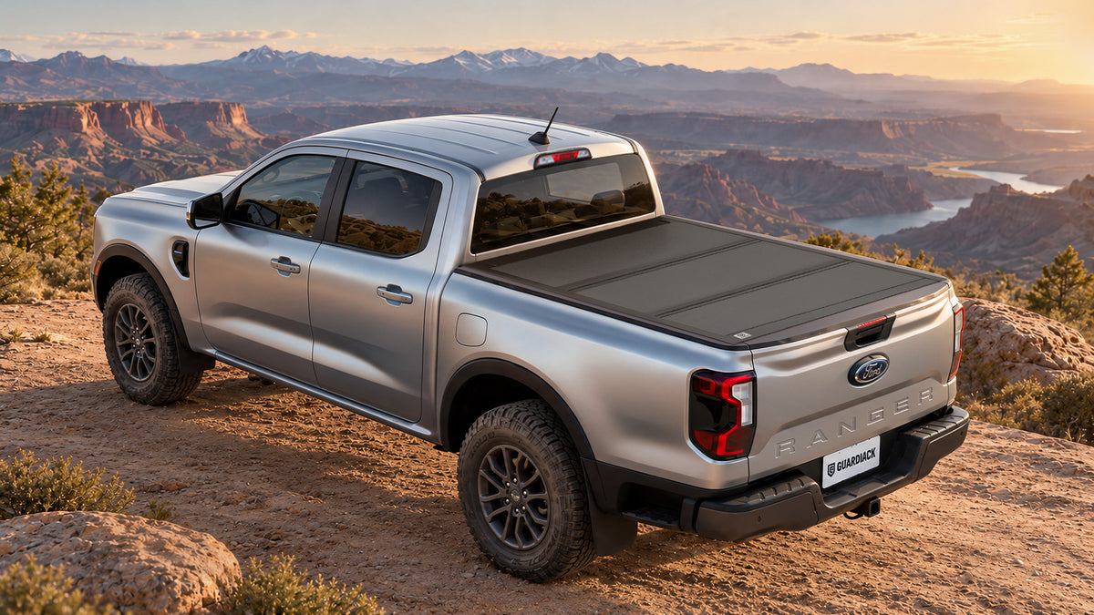 Ford Ranger bed closed with a cooler, duffels, and camping gear on a sunny mountain road