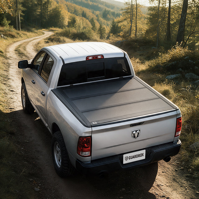 Dodge RAM 1500 Classic with a hard bed cover speeding on a gravel mountain road, dust trailing behind