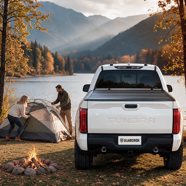 Family unpacking camping gear from an open Toyota Tundra bed beside a lakeside campsite in autumn