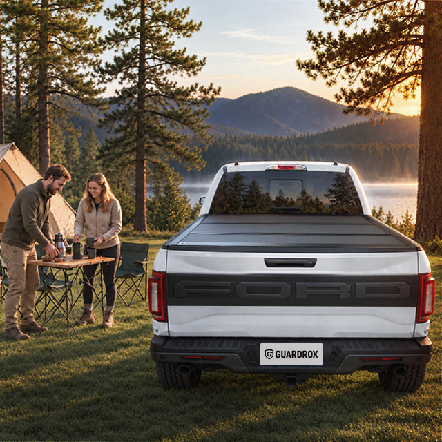 Family unpacking camping gear from an open Ford F-150 bed beside a lakeside campsite in autumn